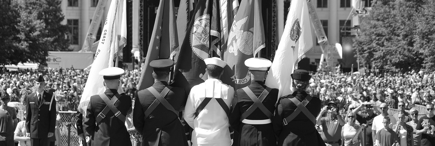 Military holding flags in front of crowd