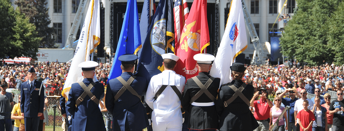 Military holding flags in front of crowd